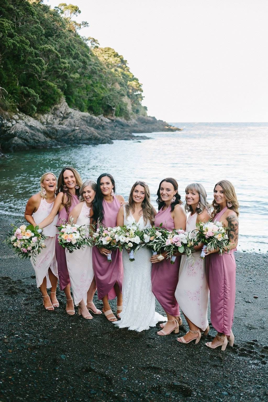 Bridal party with bouquets on a coastal beach